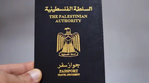 Getty Images File image of a hand holding a passport issued by the Palestinian Authority.